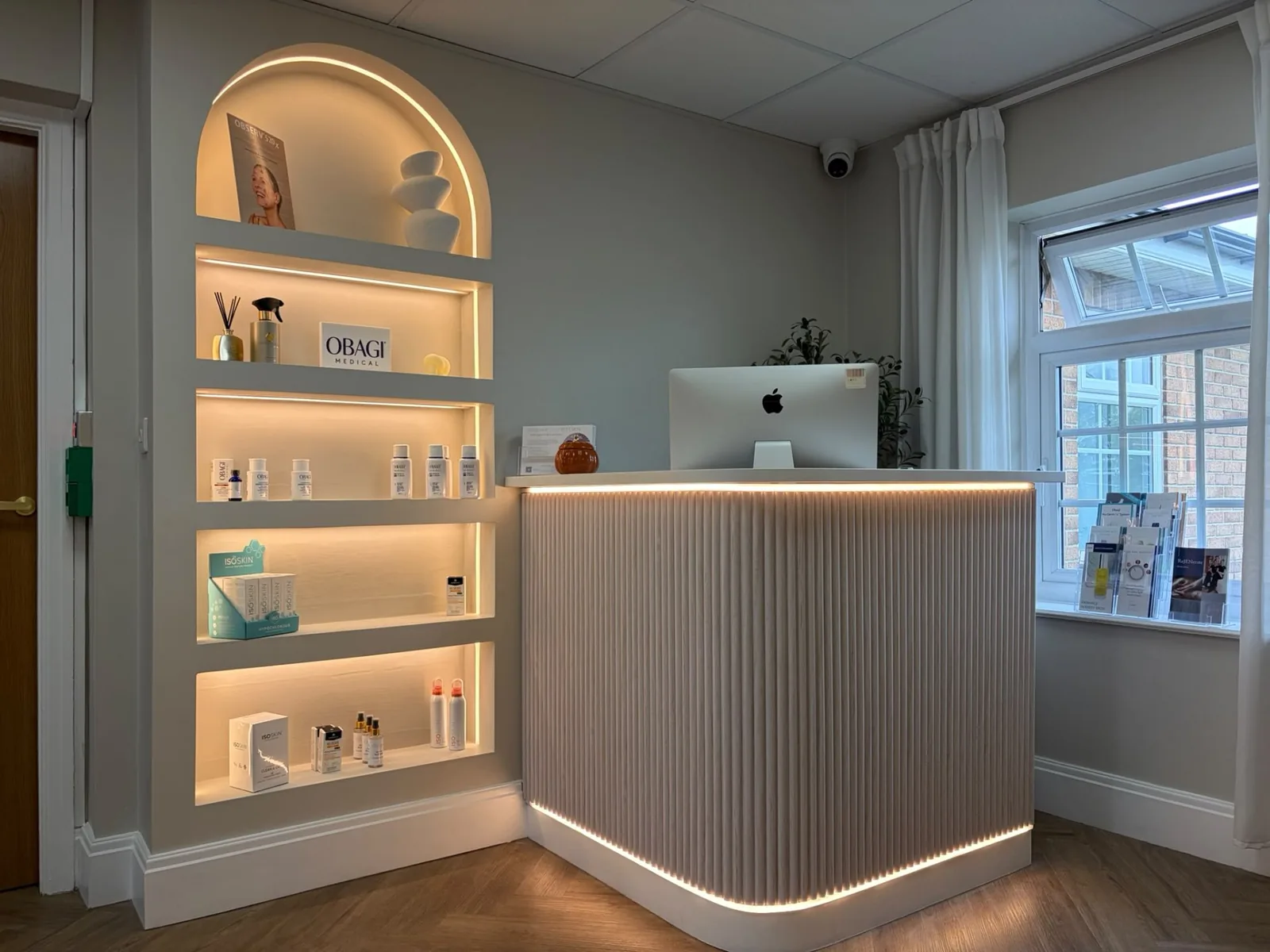 Concealed LED strip lighting around a recessed arched display shelf and a curved reception desk