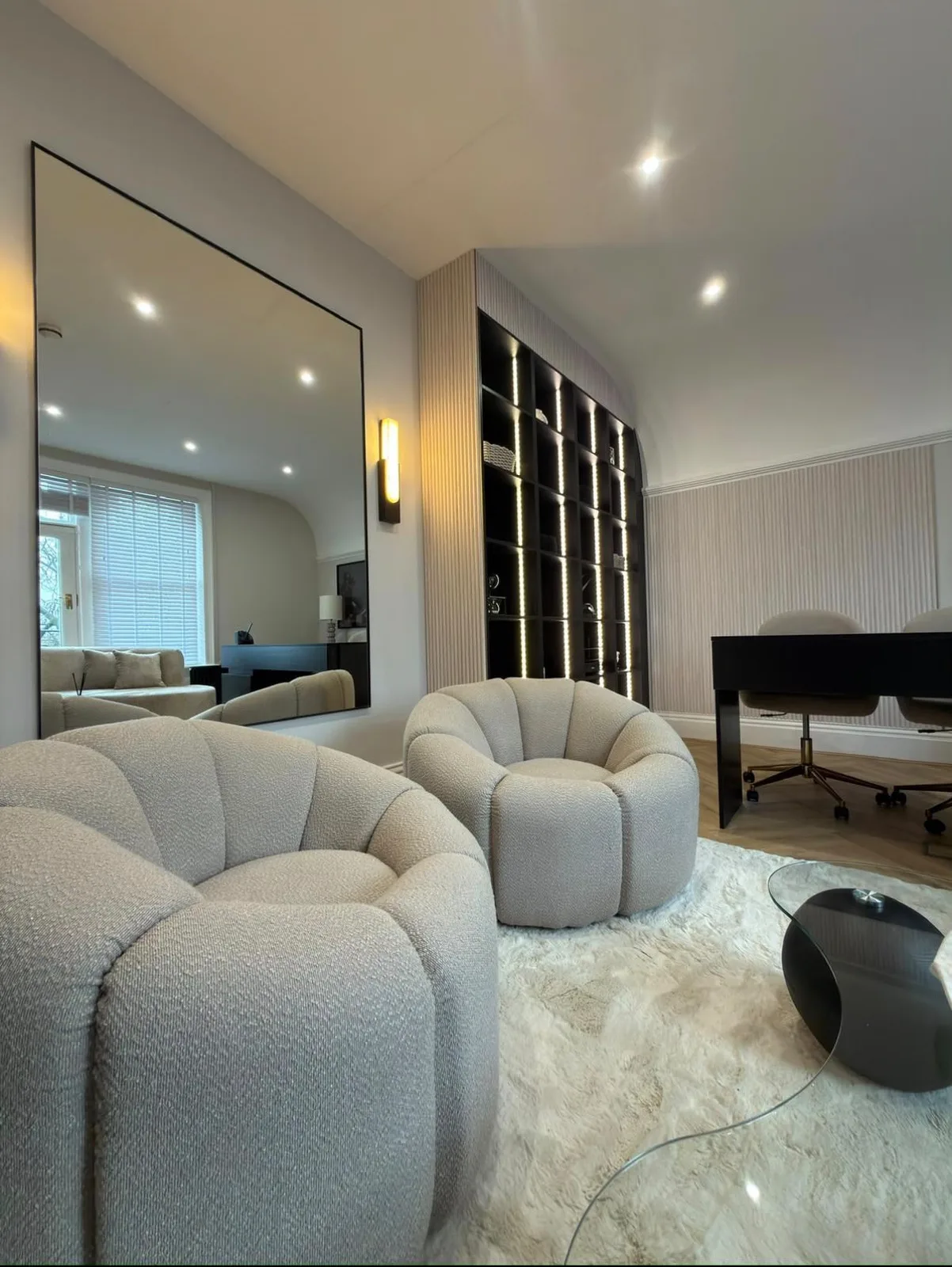 Recessed ceiling downlights, vertical LED strip lighting to a bespoke display shelving unit and a wall sconce installed in a fitted commercial interior