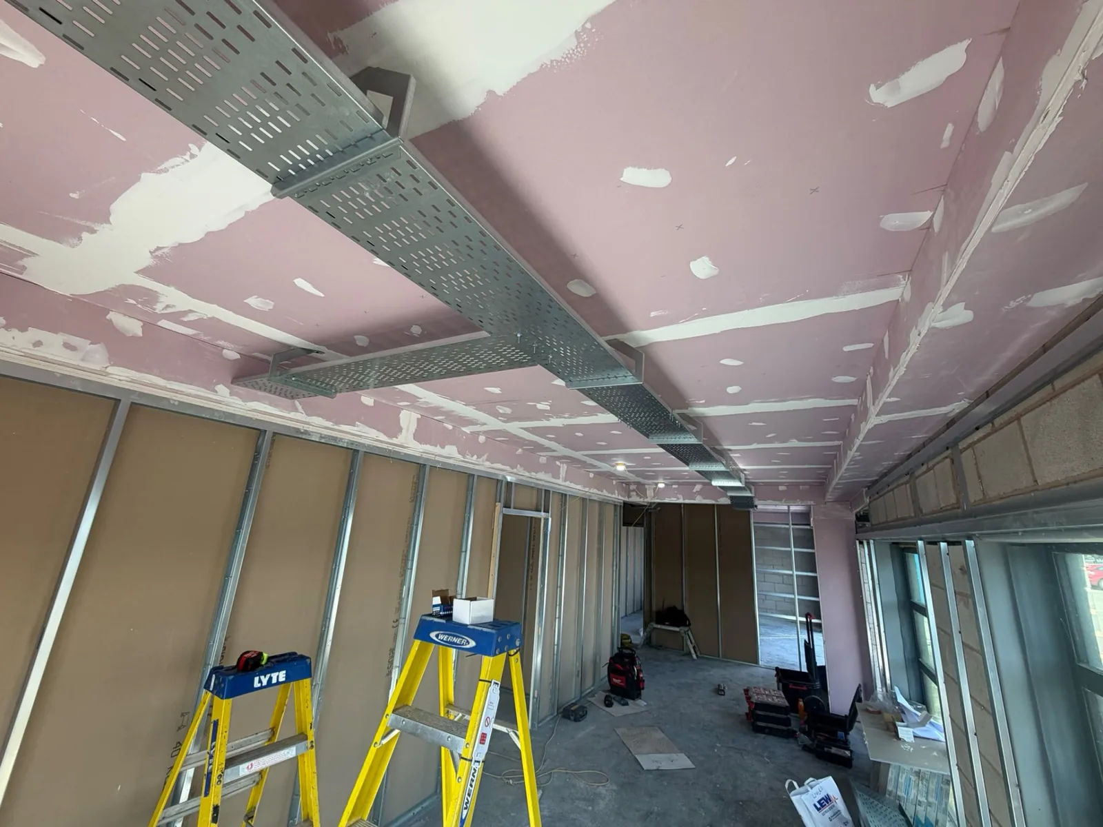 Galvanised steel cable tray containment suspended from the ceiling during a retail fit-out