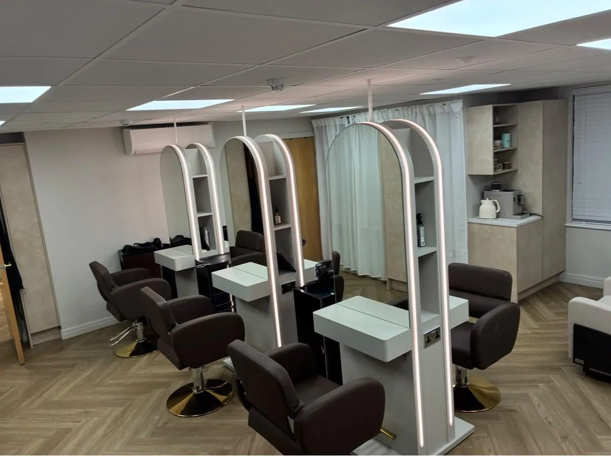 Recessed LED ceiling panels, ceiling drop-poles with sockets built into styling stations and arched LED mirror lighting installed in a salon fit-out