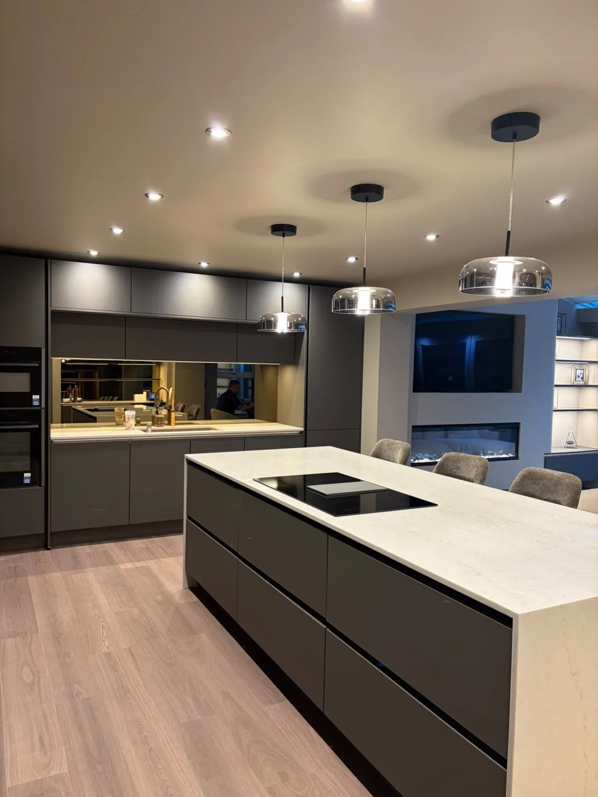 Glass pendant lights over a kitchen island with recessed downlights and under-cabinet LED strips
