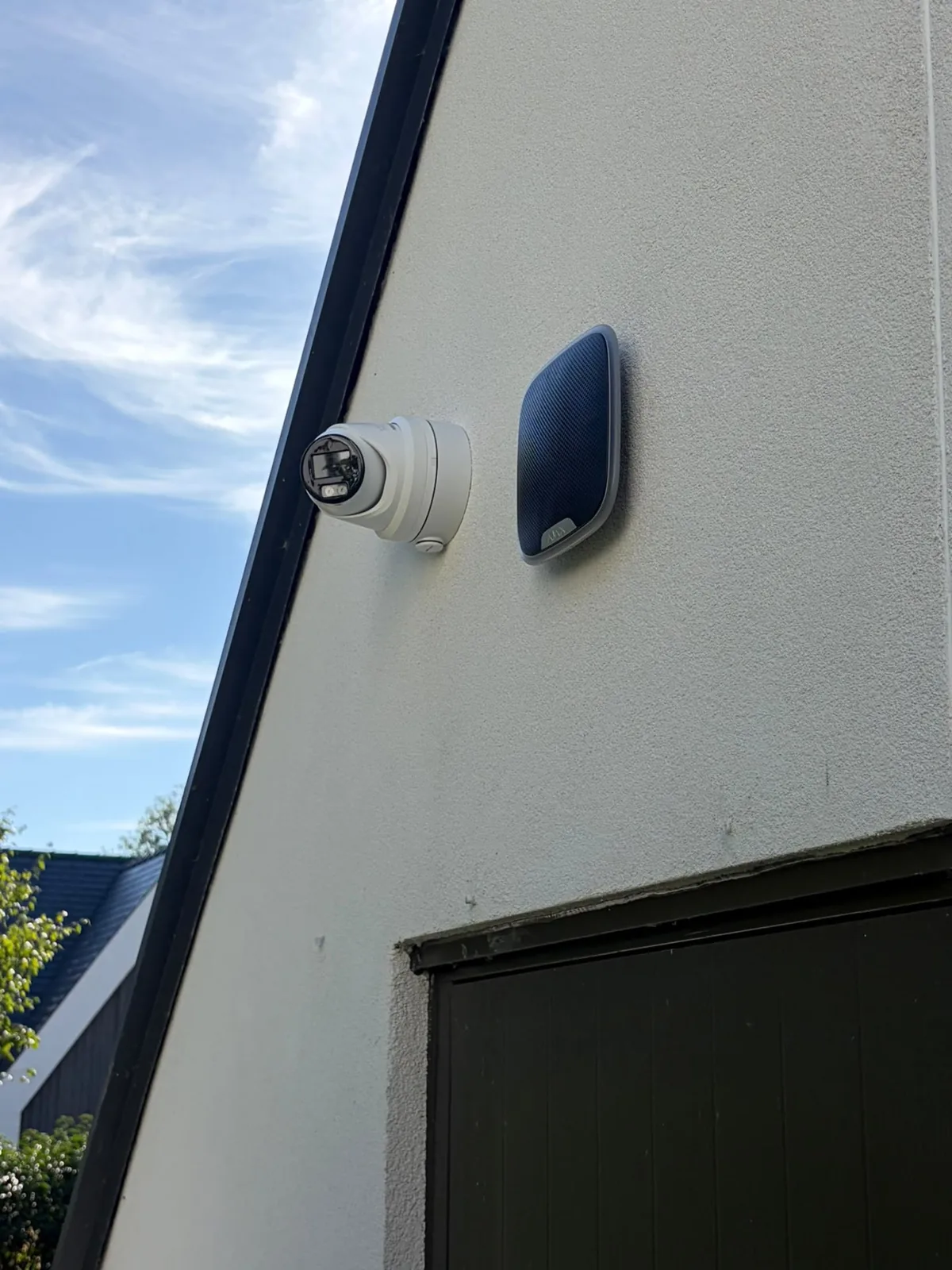 External CCTV camera and alarm sounder mounted on the outside wall of a home